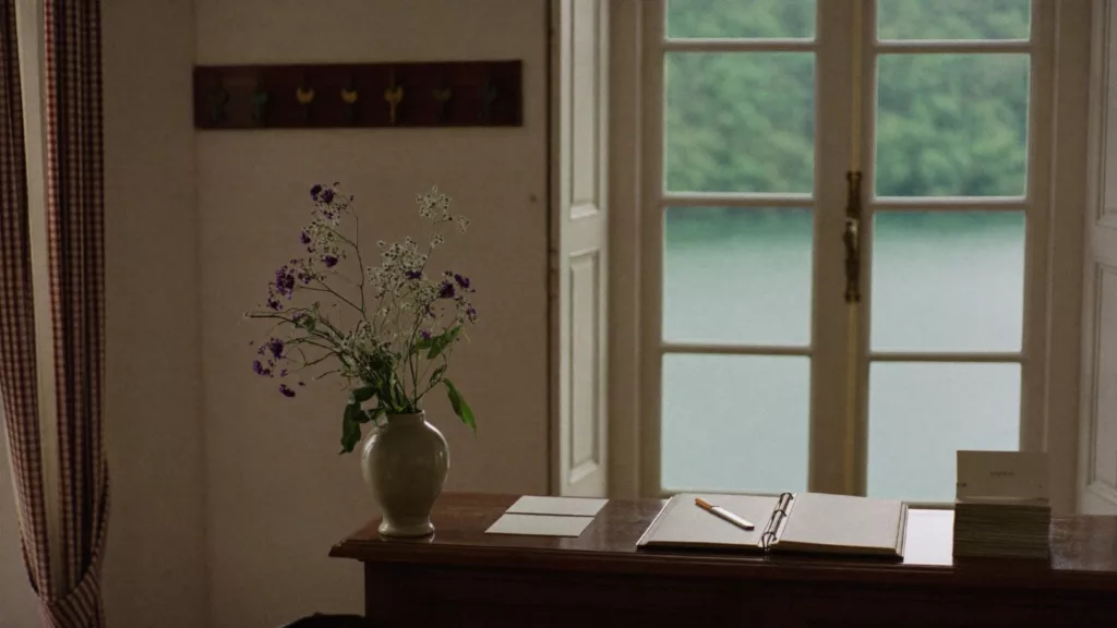 Réception d'un petit hôtel indépendant de Suisse romande au petit matin, registre ouvert et fenêtre donnant sur un lac